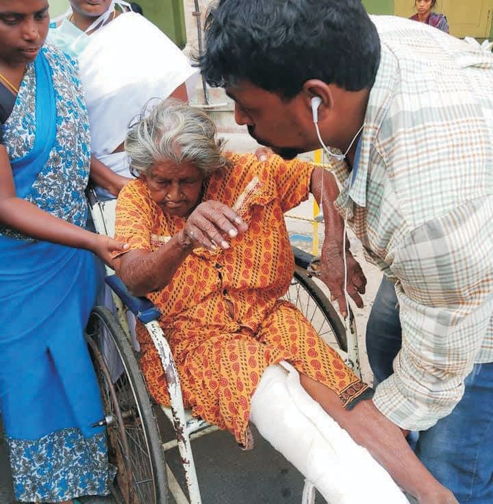 Karunai Ullangal Trust volunteers helping a frail elderly woman into a rescue vehicle in Chennai